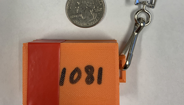 An orange encounter tracking box on a lanyard is labeled "1081" and shown next to a quarter for size. 