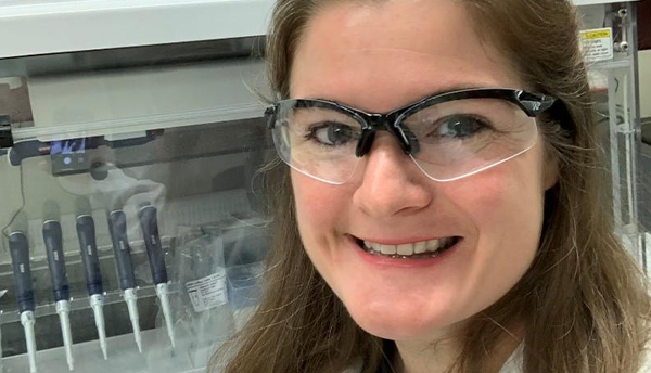 Megan Cleveland, wearing safety glasses, poses for a photo in the lab.