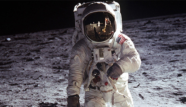 An American astronaut walks on the surface of the Moon. 