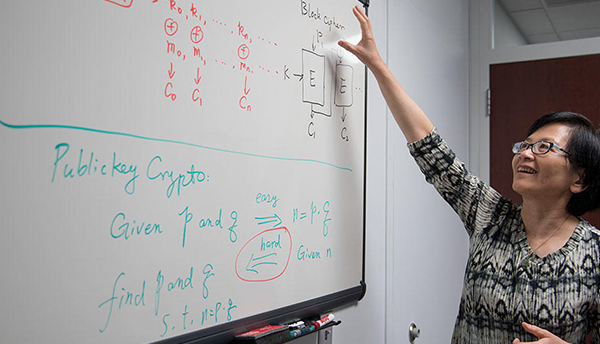 Lily Chen gestures to figures on a whiteboard. 