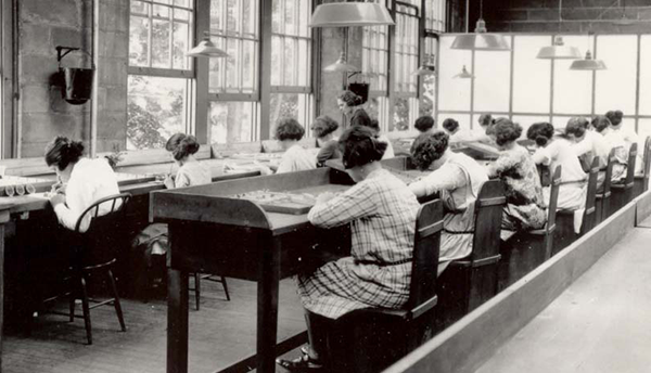 Historical photo shows women working at benches painting radium watch dials.