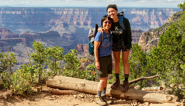 Pamela Chu and her daughter, dressed in hiking gear, pose smiling at the edge of a canyon.