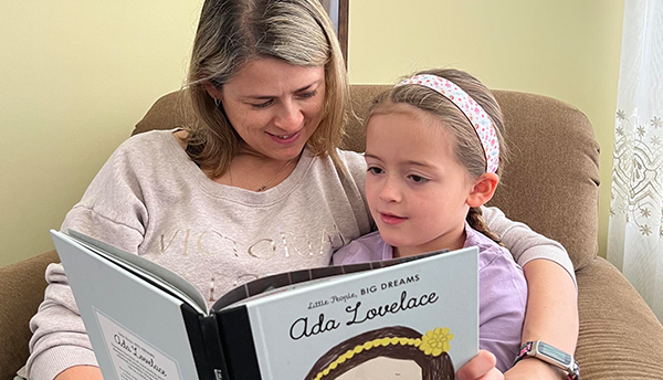 Justyna Zwolak reads a book about Ada Lovelace to her young daughter in her daughter's room at home.