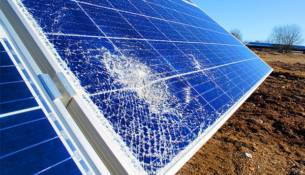 A solar panel installed outdoors is broken as if from an impact in the lower left corner. 
