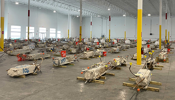 Concrete columns from the Champlain Towers South collapse lay on their sides inside a warehouse with lots of space around each one. 