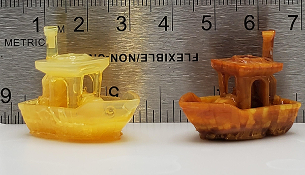 Benchy the Boat: Two miniature tugboat replicas made of resin sit in front of a metal ruler. 