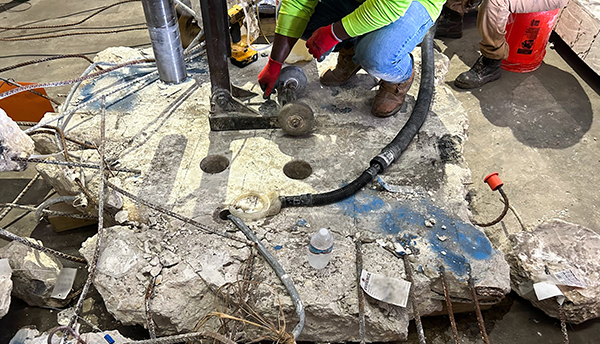A slab of concrete from Champlain Towers sits on a warehouse floor as researchers use equipment to extract core samples. 