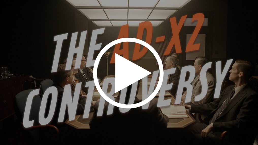Video title screen reads "The AD-X2 Controversy," over a still of men in 1950s suits sitting around a conference table. 
