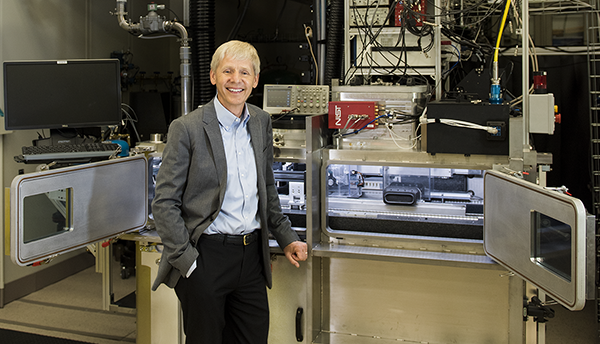 NIST Chief Metrologist Jim Olthoff stands in front of equipment in a lab. 