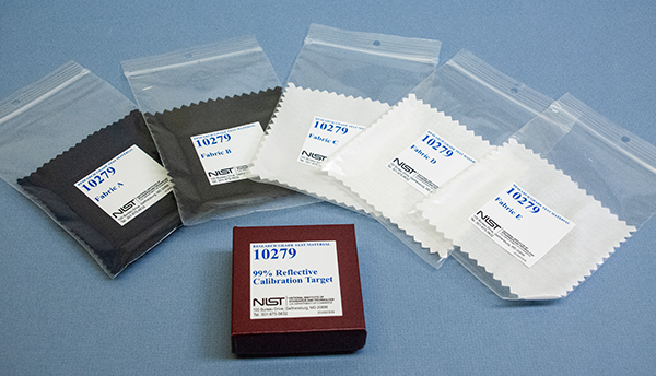 Five fabric swatches in clear plastic bags labeled 10279 are arrayed around a box labeled 99% Reflective Calibration Target. 