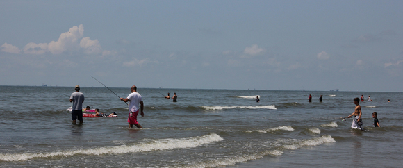 People fishing and wading in the water on Elmer's Island beach.