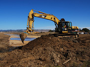 An excavator digs into the soil at a restoration project site.