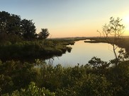 The sun heads down above a Maryland marsh, the blue sky reflecting off the still water.