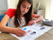 A kid doing homework at the dinner table.