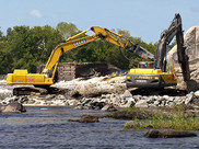 Two excavators demolish a dam