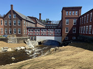 A river runs under a bridge and between several buildings.