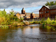 A river flows past several historic brick buildings