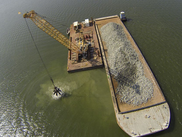 A crane moves hard substrate from a barge into the Piankatank River to construct an oyster reef. Photo: U.S. Army Corps of Engineers