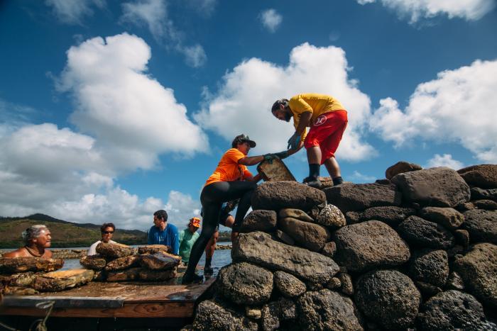 Community members come together to restore the walls of a traditional Hawaiian fishpond.