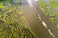 Aerial view of two recreational boats crossing marsh-lined waters in Louisiana.