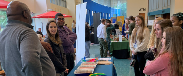 People talking, gathered around an outreach table.