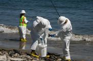 Scientists in protective suits scan Refugio Beach for oil pollution.