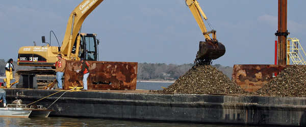 heavy machinery on a barge digging into piles of oyster cultch. Credit: Outdoor Alabama/David Rainer