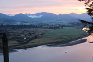 Aerial view of wetlands and fields along a river, with mountains in the background