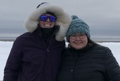 two women in parkas standing outside on snow and ice