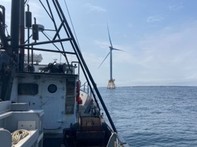 a wind turbine in the ocean seen from a fishing vessel