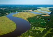 A river snakes between marshland, forest, and residential areas.