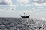 Fishing vessel with trawl booms deployed at sea