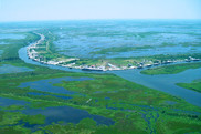 Aerial view of a community bordering a waterway, surrounded on all sides by wetlands.