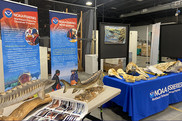 exhibit booth with colorful NOAA signage, handouts, and marine mammal bones on display
