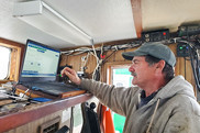 Fisherman in the wheelhouse of a vessel monitoring electronic data disap0ly