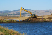Construction equipment digging a channel in a wetland