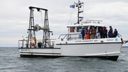 Small, white research vessel on the water, photographed from the side