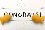 The word congratulations with a fish-shaped cheese3 crackeron either side of the word