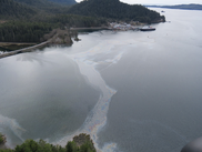 An oil slick goes from bank to bank in a body of water with tree covered hills in the background. Credit: U.S. Coast Guard