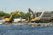 Two heavy construction machines demolish a dam. Credit: Penobscot River Restoration Trust