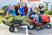 group shot of people handling landscaping equipment in from of a building