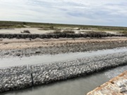 Large wire mesh baskets filled with rock on coast.