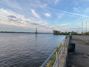 A river flows next to a paved trail with a metal railing.