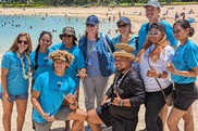 A group of 10 volunteers and staff in matching shirts pose for a photo on a beach. Credit: Kuleana Coral Reefs.