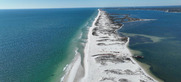 A narrow sand island sits between blue water on either side.