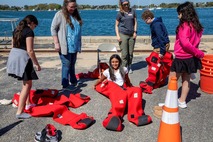 children trying on bright red ocean survival suits