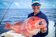 female angler excitedly holds up a large red snapper