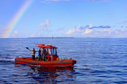 red boat on the water under a rainbow