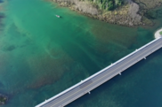 Aerial image of a river with a road spanning across it and a boat in the background.