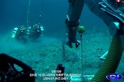 Underwater view of the seafloor  with ROV arms deploying coral fragment racks and saturation divers in the back. Credit: NOAA, C-Innovation, LLC.